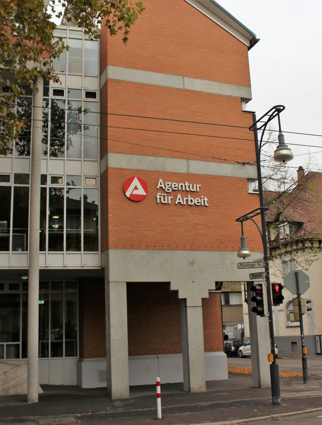 Gebäude aus rotem Backstein und Beton mit der Aufschrift 'Agentur für Arbeit'.