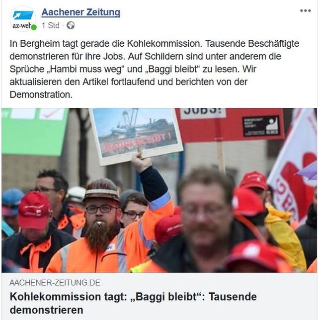 RWE-Mitarbeiter demonstrieren in roten Arbeitsjacken. Zeitungstitel: "Kohlekommission tagt: 'Baggi bleibt'. Tausende demonstrieren.