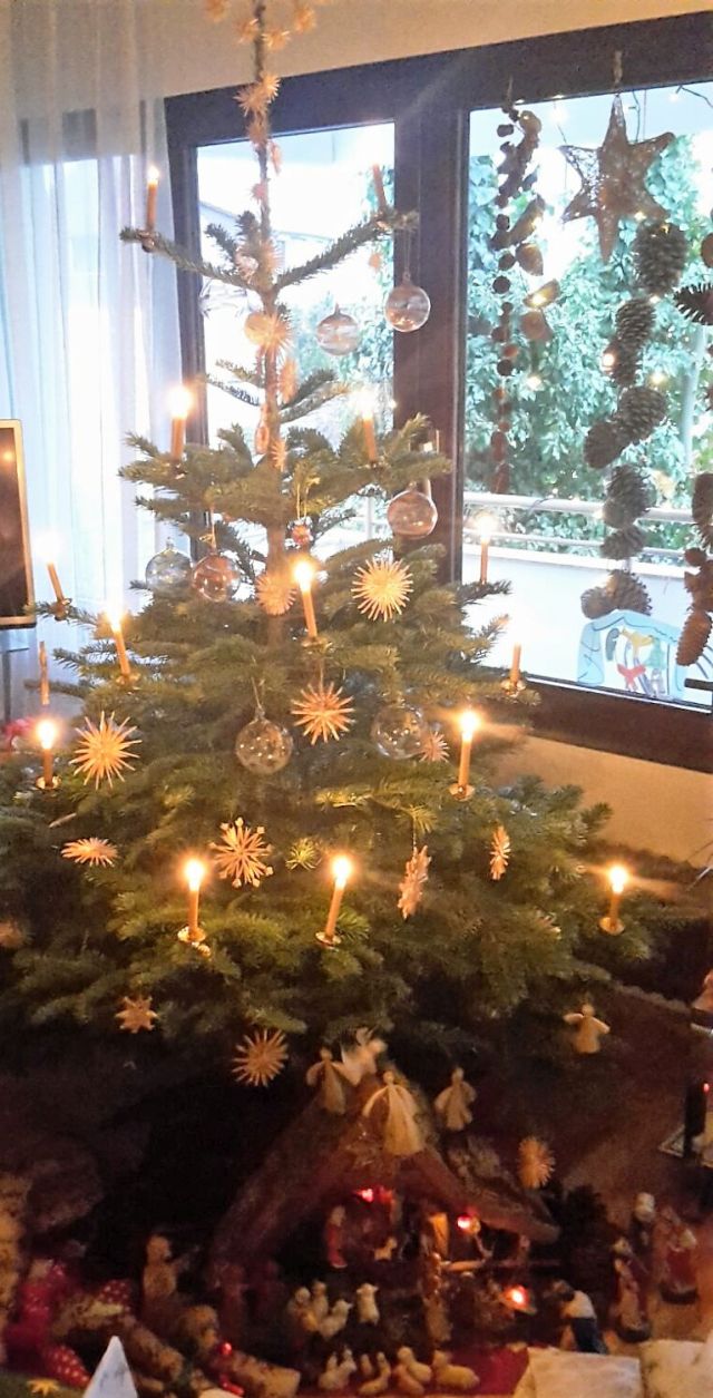 Weihnachtsbaum mit brennenden Kerzen und Glaskugeln.