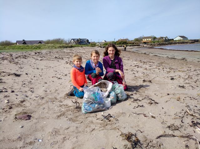 Drei Kinder mit dem aufgesammelten Strandgut. 
