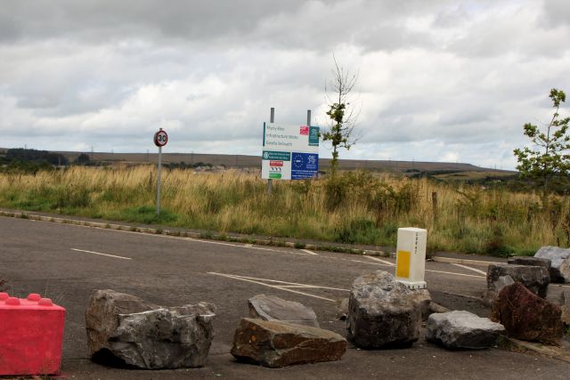 Die Zufahrt zu einem Gewerbegebiet ist mit Felsbrcken abgesperrt. Ein Schild zeigt die EU als Förderer des Gewerbegebiets, das leersteht.