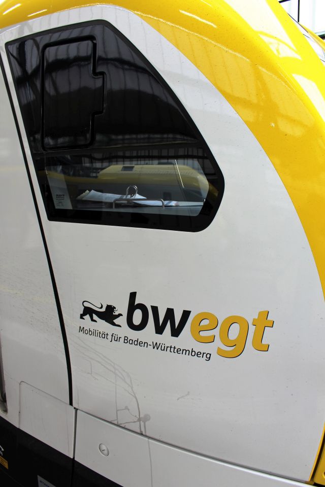 Das Foto zeigt einen Teil der Zugführerkabine von außen. Weiß und gelb sind die Farben. Schriftzug "bwegt. Mobilität für Baden-Württemberg".