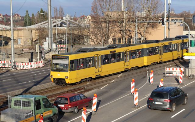 Gelbe Straßenbahn fährt über eine Brücke.
