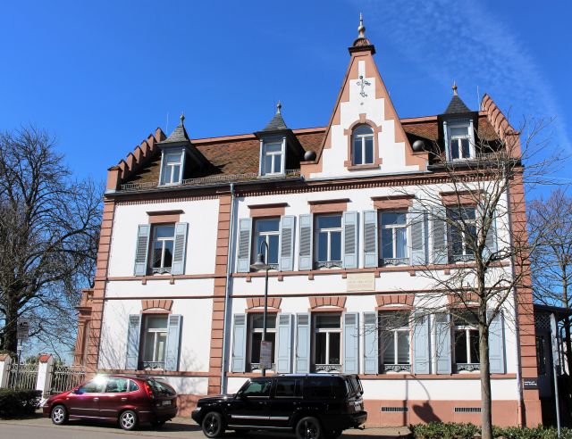 Wohnaus von Carl Benz in Ladenburg. Weiße Fassade mit rötlichen Begrenzungen.