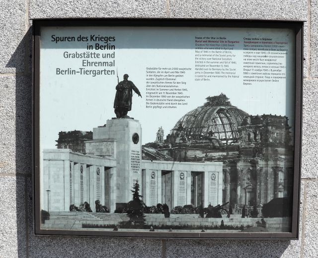 Schaukasten mit einem dreisprachigen Text und einem historischen Foto, das im Vordergrund das Sowjetische Ehrenmal und im Hintergrund den zerstörten Reichstag zeigt.