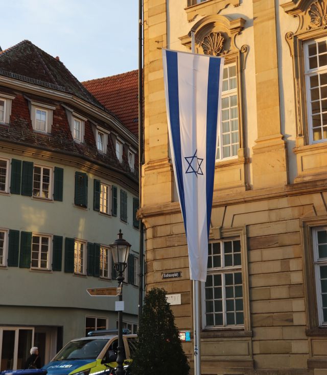 Die israelische Fahne - blaue Streifen und ein blauer Davidstern in der weißen Mitte - hängt vor einem Gebäude aus Sandsteinquadern.