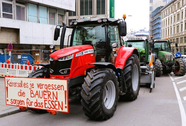 Ein rooter Traktor mit einem Plakat: 'Keiner soll es vergessen, dieBauern sorgen für das Essen!'
